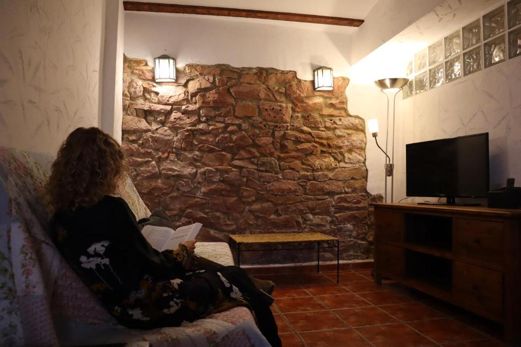 ヴィラファメスにあるLA COVETA - Aptos. Vilapartの石壁の部屋のソファに座る女性