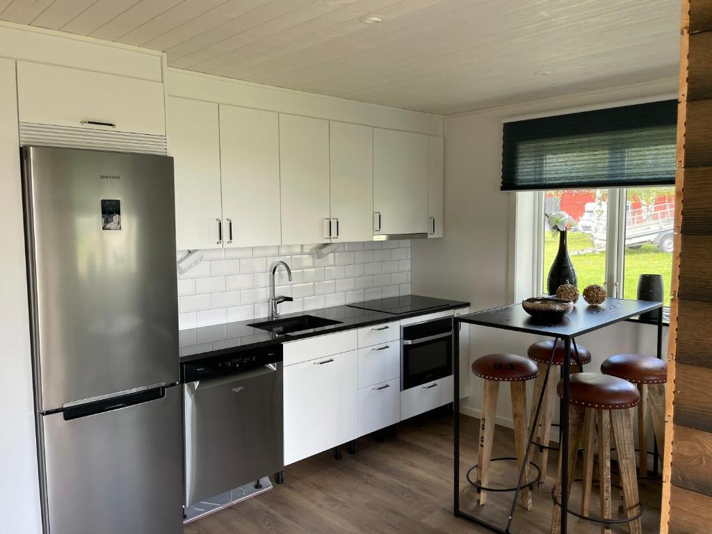 a kitchen with white cabinets and a stainless steel refrigerator at Hälla 1 nära jönåkers golfbana in Jönåker