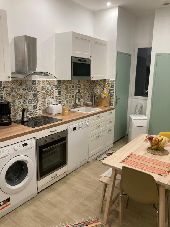 a kitchen with white cabinets and a sink and a table at Charmant F4 proche de la gare Saint Charles in Marseille