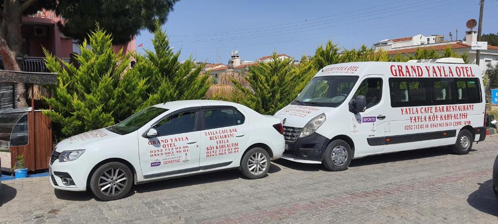 two white vans parked next to a small car at Grand Yayla Hotel in Çeşme