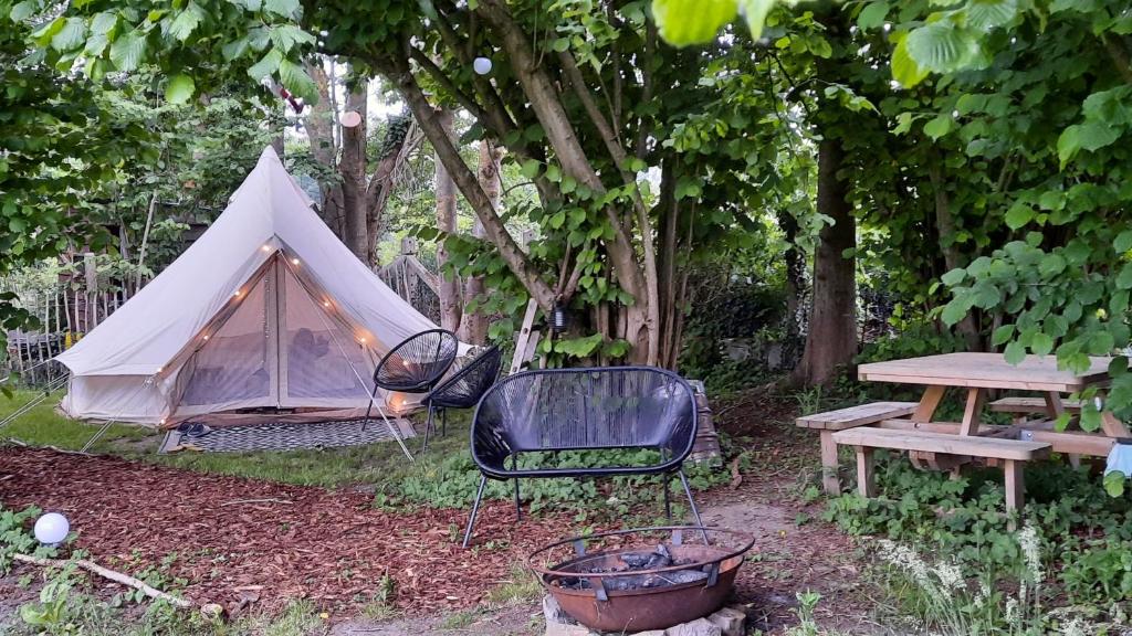 Herzele的住宿－Glamping Zonnebloem - Back-to-Nature，帐篷、椅子、桌子和长凳