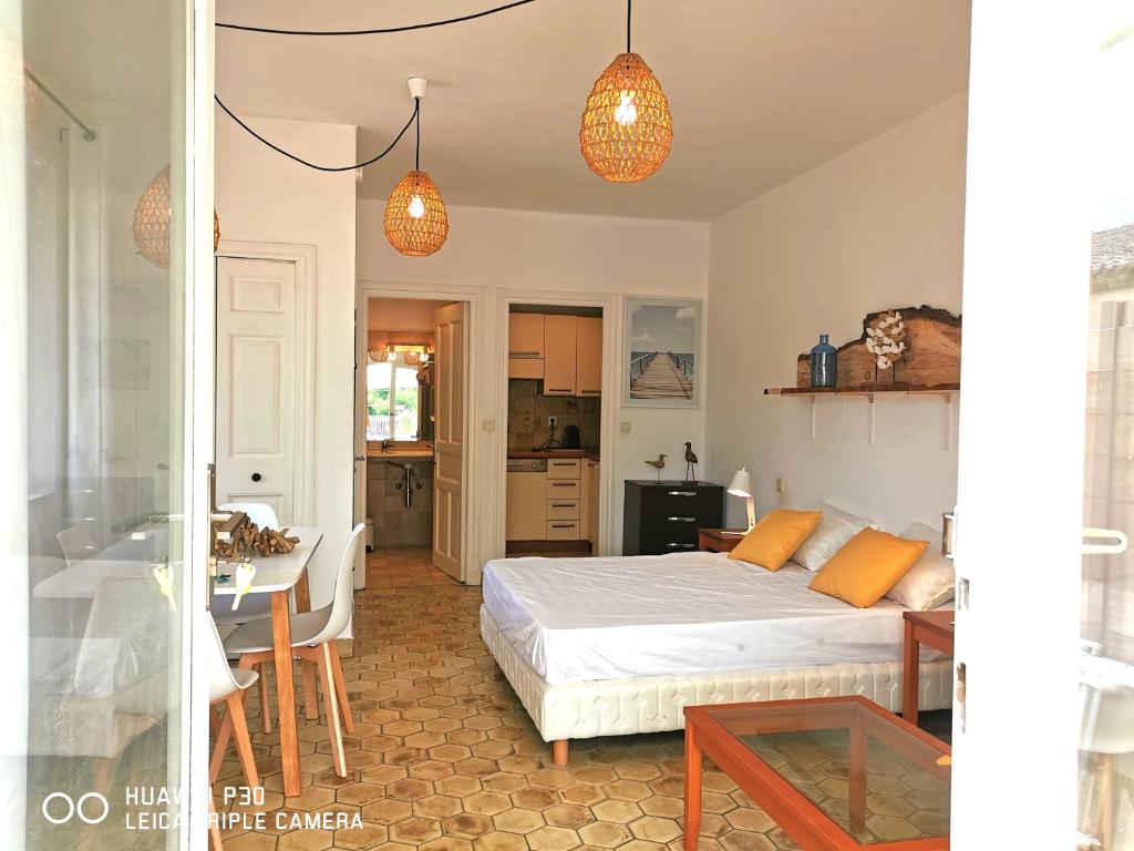 a bedroom with a bed and a table and a kitchen at Studio 1 - LES SUITES DE ROBINSON - Résidence avec piscine en bord de Siagne, à Mandelieu-La-Napoule in Mandelieu-la-Napoule