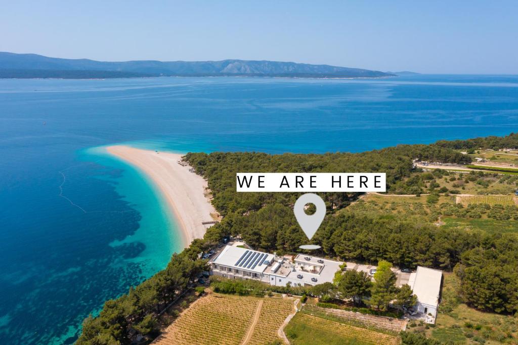 an island with a sign that says we are here at Zlatni Rat Beach Resort in Bol
