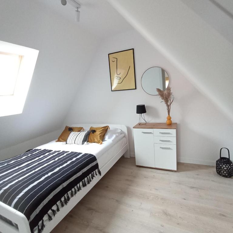 a white bedroom with a bed and a mirror at Apartament Pod Bzem Puck in Puck