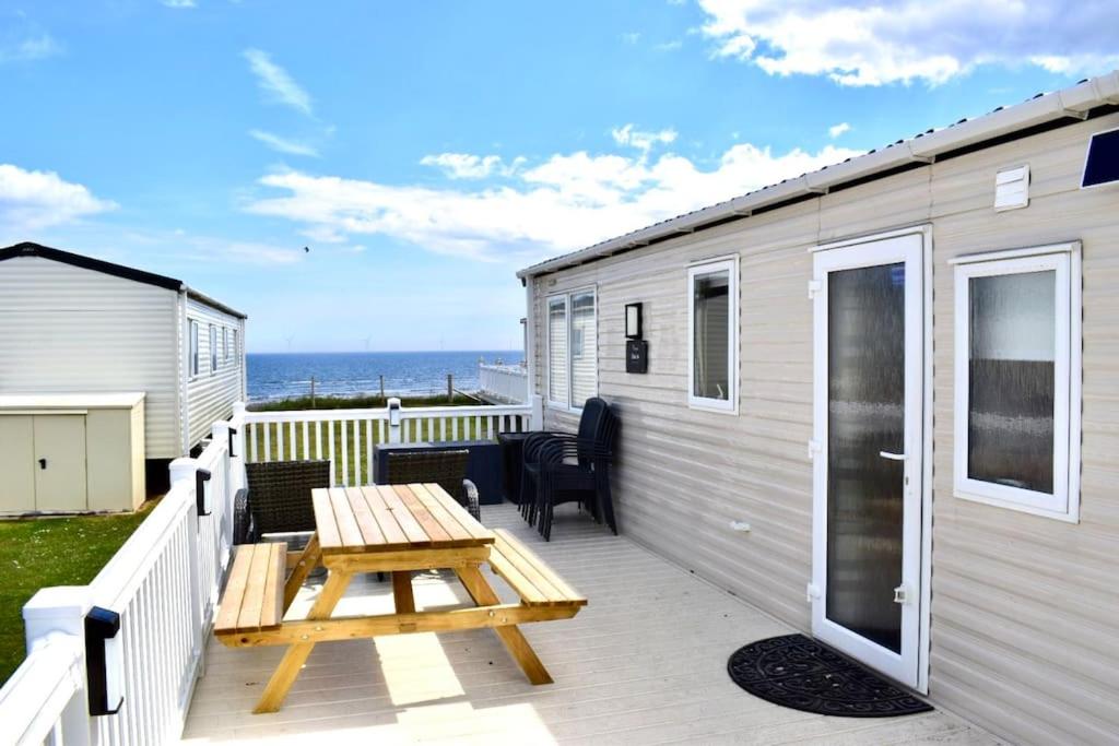 una terraza con una mesa de picnic y una casa en New Sea View Platinum Caravan with Huge Decking en Newcastle