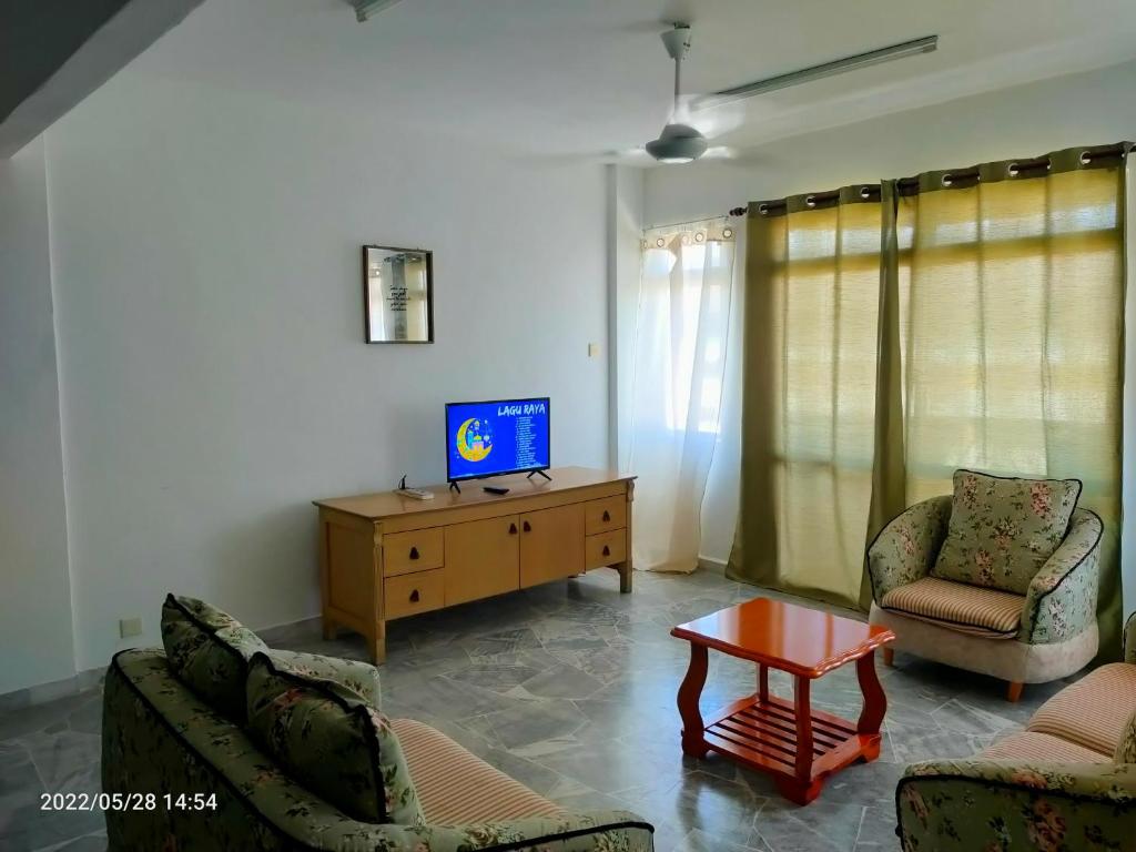 ein Wohnzimmer mit einem Sofa, einem TV und einem Tisch in der Unterkunft Deluxe Family Beach Condo PortDickson in Port Dickson