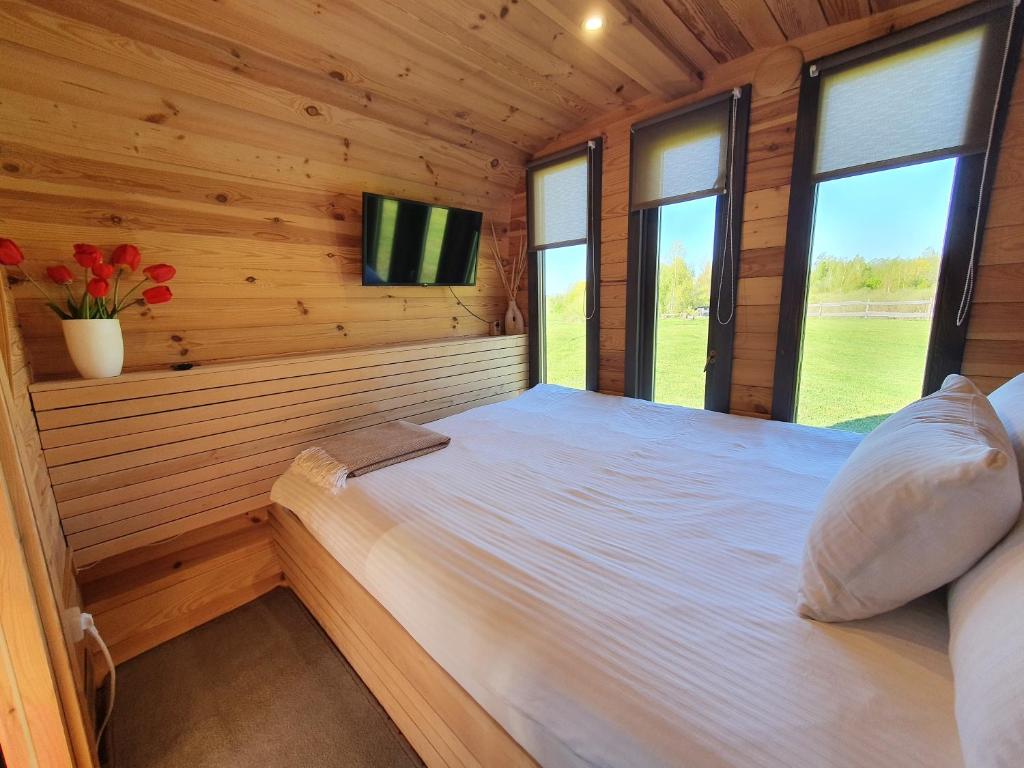 a bedroom in a log cabin with a bed and a tv at Purenes - Barrel shaped pod with hot tube in Sliseri