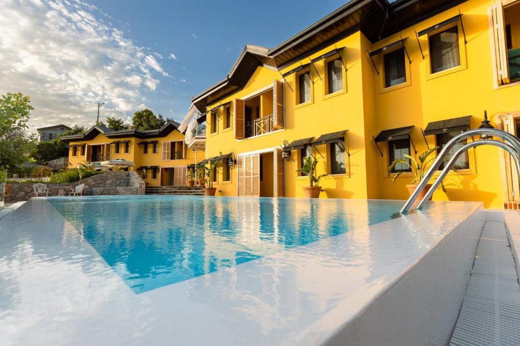 une piscine en face d'un bâtiment jaune dans l'établissement PANJUR SÖĞÜT, à Marmaris