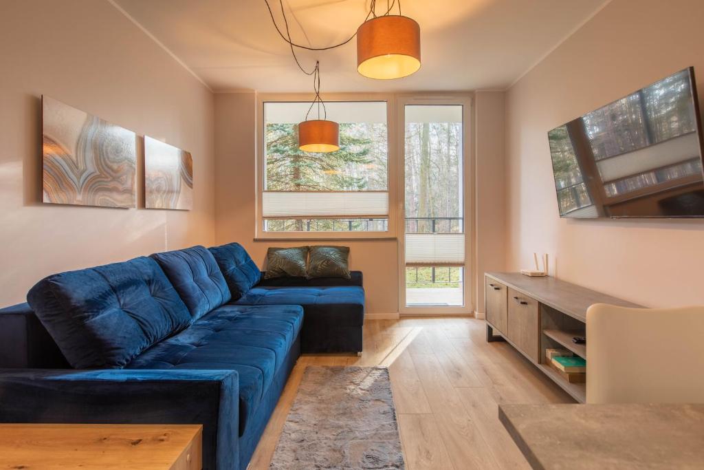 a living room with a blue couch and a table at Apartament Jelonek Zdrój in Polanica-Zdrój