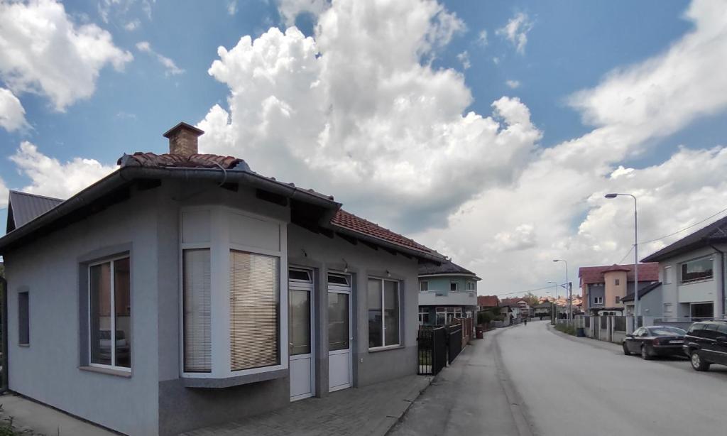 a small house on a street with a cloudy sky at Apartman HAX in Sjenica