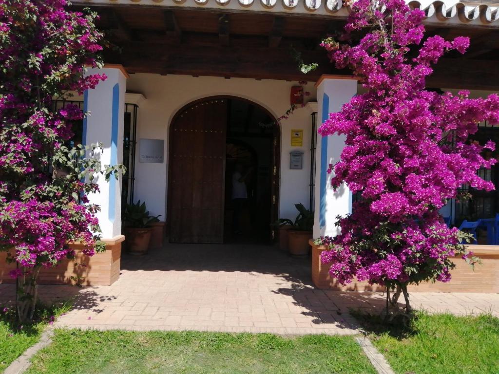 un bâtiment avec des fleurs violettes devant lui dans l'établissement El Rocío Azul Alojamiento Rural, à El Rocío