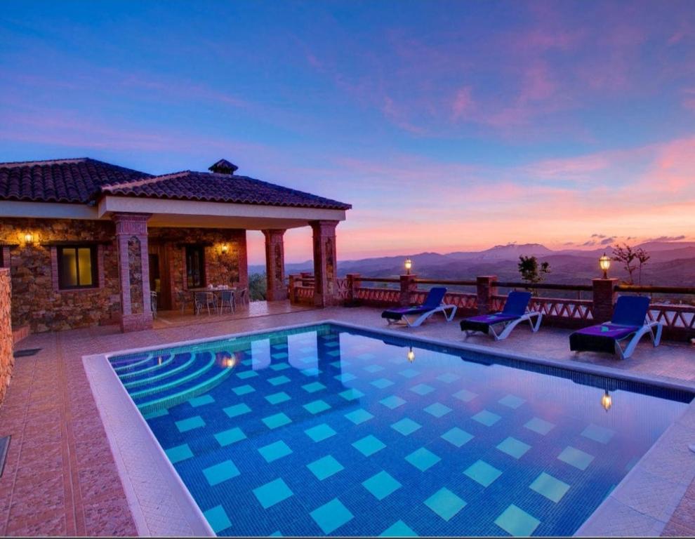 a swimming pool in front of a house at La Olgava in El Gastor
