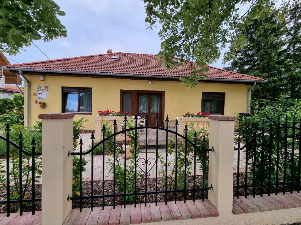 uma casa com um portão em frente em Muskátlis Ház em Balatonlelle