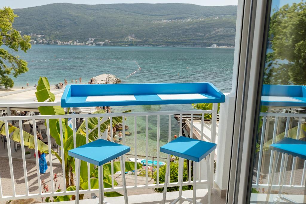 balcón con taburetes azules y vistas a la playa en Tamaris beach apartment, en Herceg-Novi
