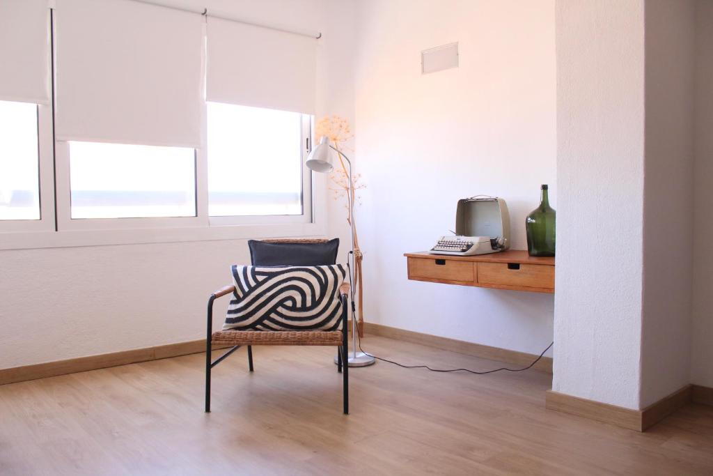 een stoel in een kamer met een bureau en een televisie bij A Nossa Casa da Costa in Costa da Caparica