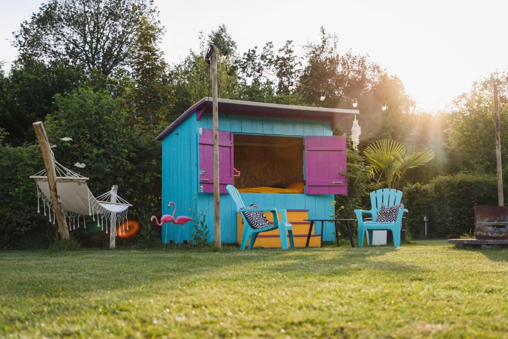 Une cabane bleue et rose avec des chaises dans une cour dans l'établissement Caribbean Bedstee voor 2 personen, à Paasloo