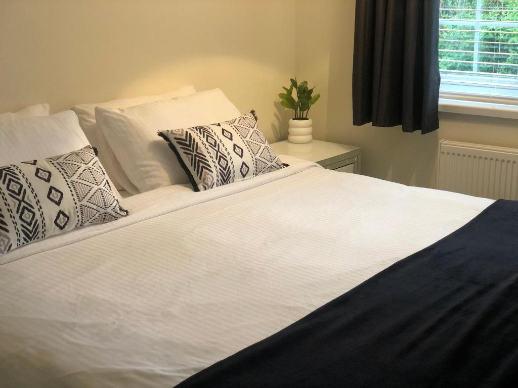 ein großes weißes Bett mit Kissen und einem Fenster in der Unterkunft HALLSTEAD in Skegness