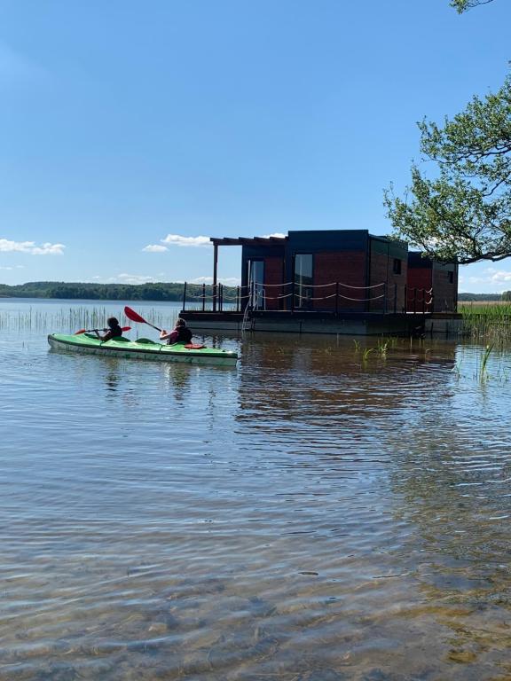 una persona en un kayak en un lago con una casa en "B" Domek na wodzie Warmińskie Pompeje, en Barczewko