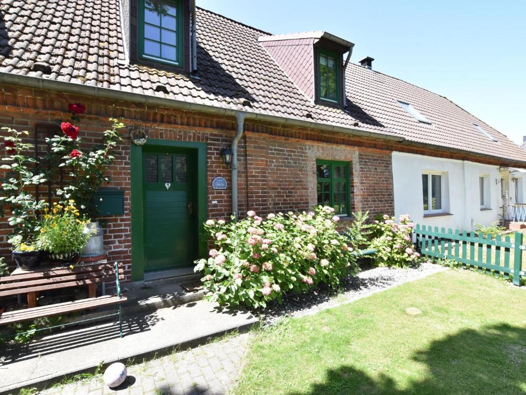 a brick house with a green door and some flowers at Spacious Holiday Home in Landstorf Zierow with beach nearby in Zierow