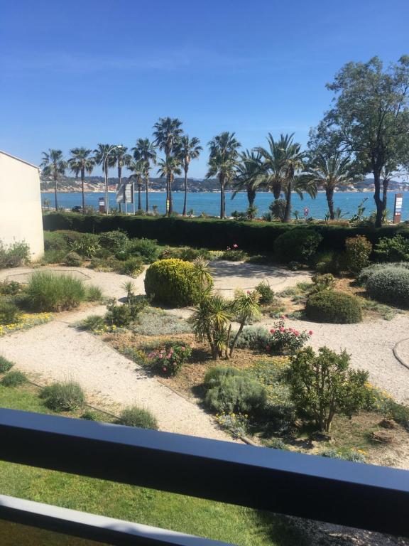 una vista di un giardino con palme e l'oceano di C'est la vie a Sanary-sur-Mer