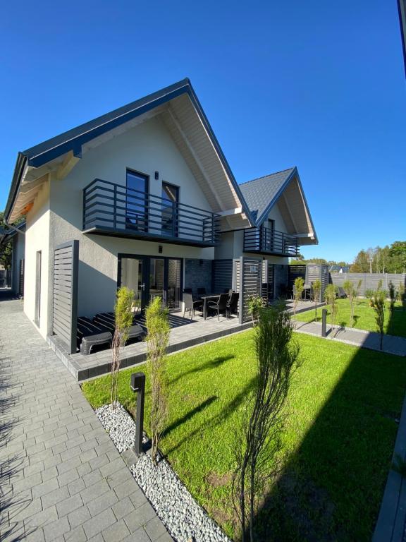 a house with a green lawn in front of it at Zagroda Liliowa in Dębki