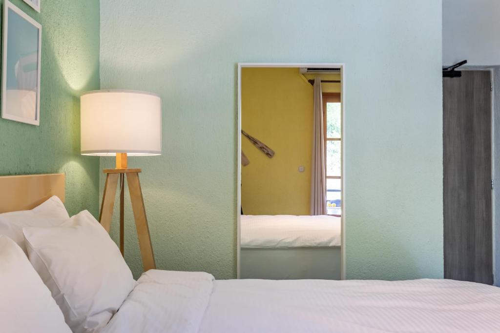 a bedroom with a bed and a lamp and a mirror at Panormos Beach Hotel Skopelos in Panormos Skopelos