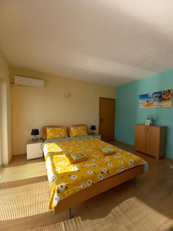 a bedroom with a large bed with a yellow blanket at PS Apartments - Peshtani in Peštani