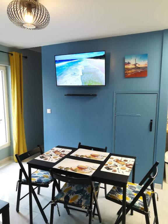 une salle à manger avec une table et une télévision sur un mur bleu dans l'établissement Promotion du Jour - Le Figuier, à Deuil-la-Barre