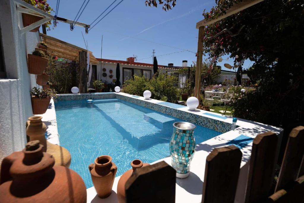a swimming pool with vases sitting next to a house at Beach House Babylon guest house with kitchenette and garden in Torreira