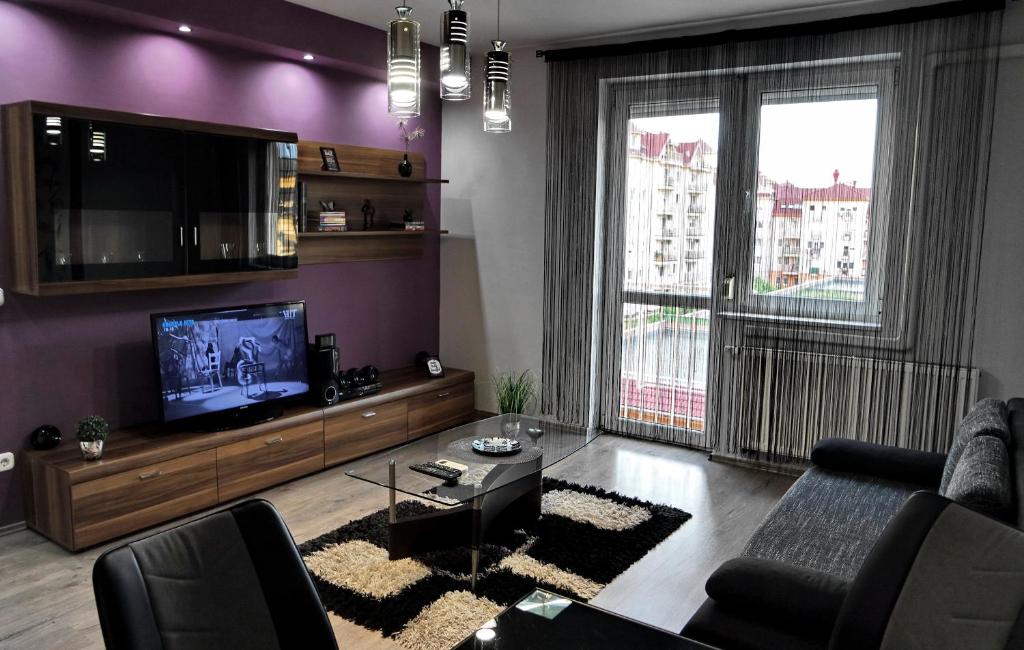a living room with purple walls and a tv at Nidius Apartment in Debrecen