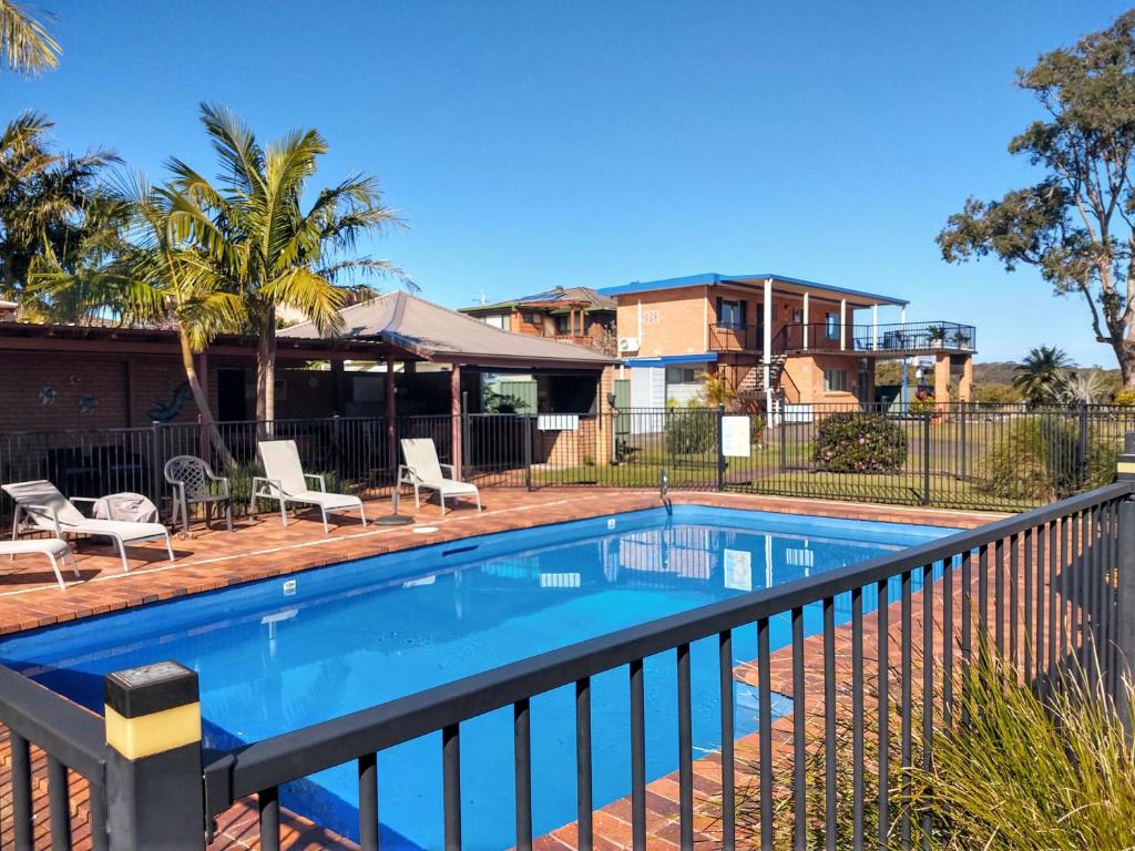 a swimming pool with chairs and a house at Haven Waters Motel & Apartments in North Haven