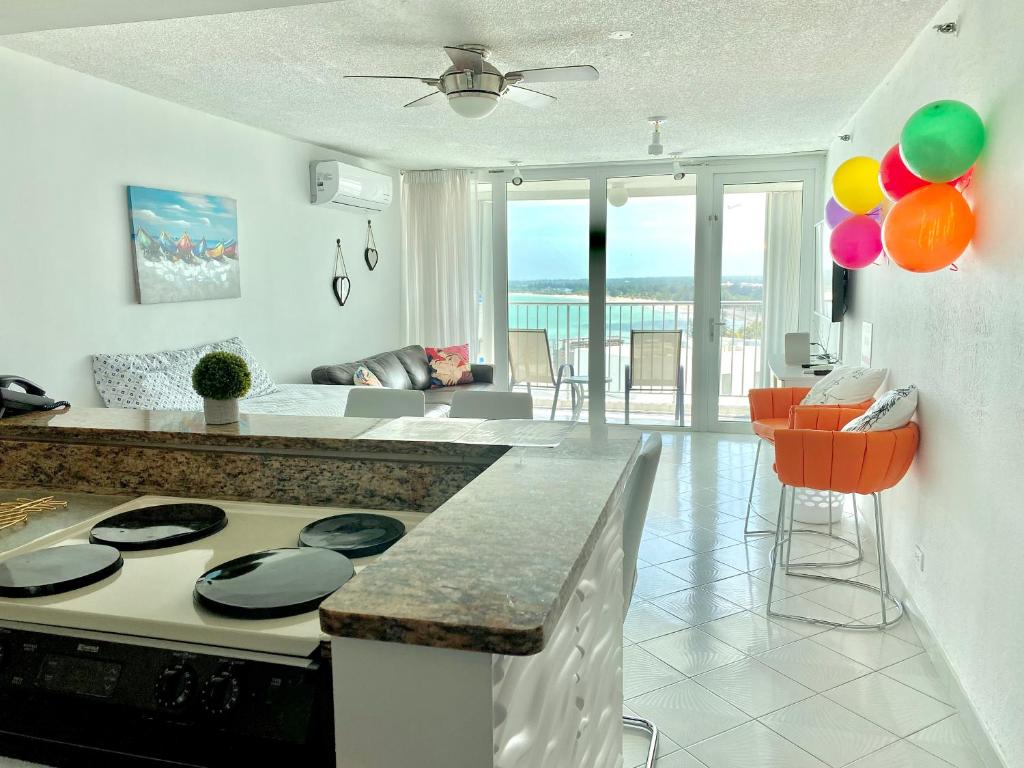 a kitchen with a stove and a living room at Private Apartment at Maré St Clair Hotel in San Juan