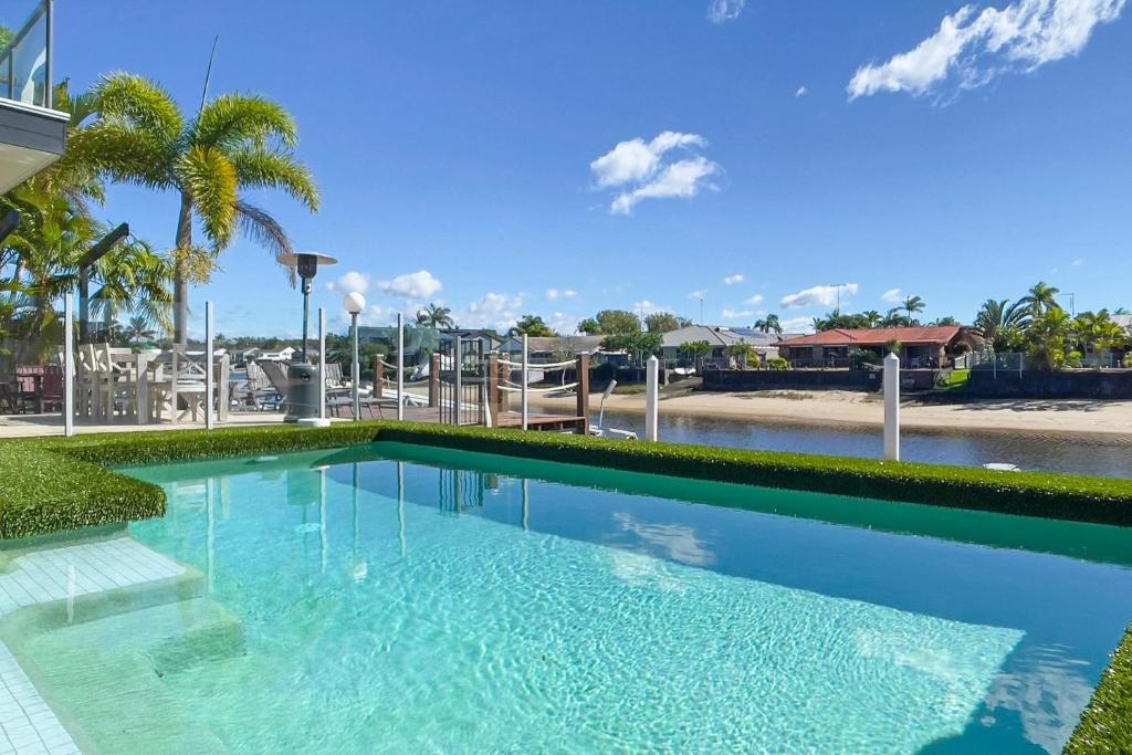 uma piscina com água azul e palmeiras em Remarkable Six Bedroom Waterfront Home! Perfect for the extended family em Mooloolaba