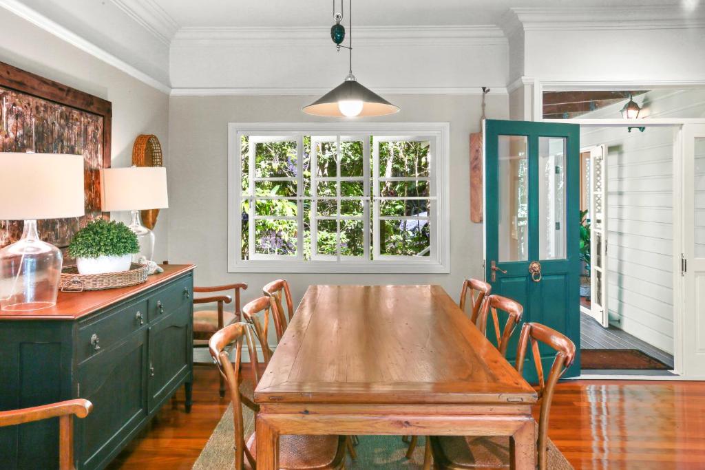 a dining room with a wooden table and a green door at Stoney Creek Cottage in Caravonica