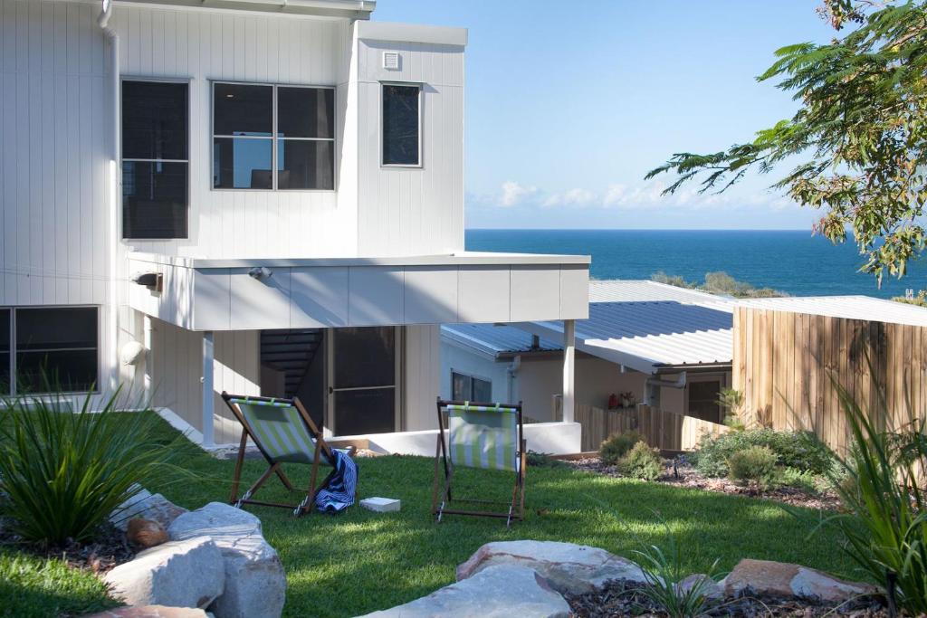 dos sillas sentadas en el césped frente a una casa en Coolum Beach Holiday House, en Coolum Beach