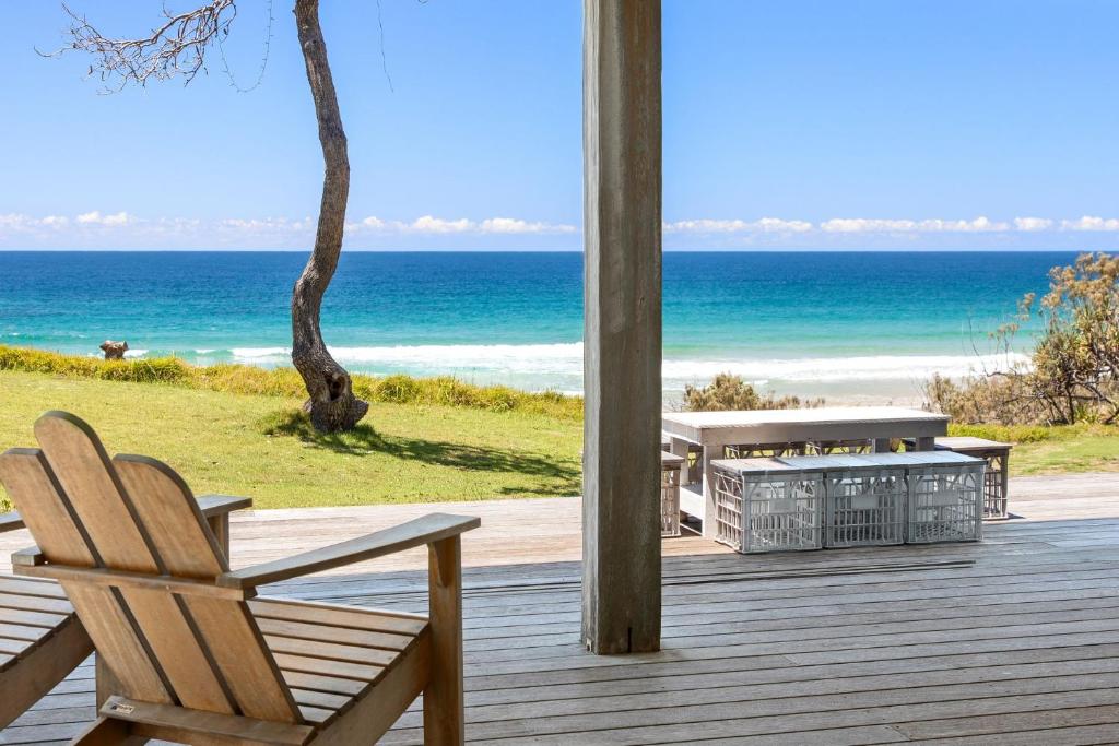 a wooden porch with a chair and the ocean at Saltwater Beach House in Yaroomba
