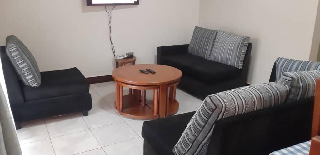 a living room with two chairs and a table at Candle Wood Homes in Lira