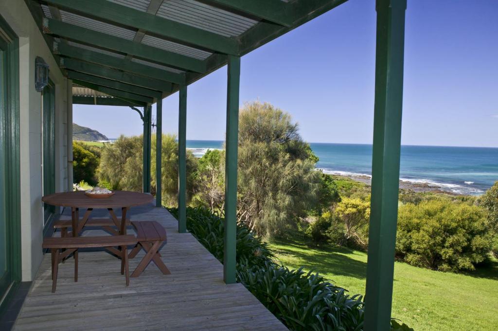 a porch with a table and a view of the ocean at Bennetts Beach House in Apollo Bay