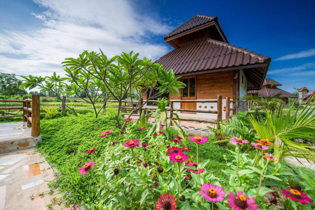 a garden with flowers in front of a house at Panya Garden Resort in Ban Huai Na (1)