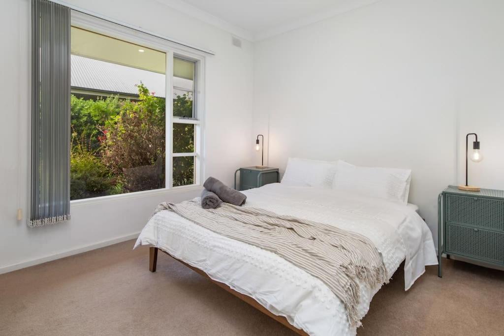 a white bedroom with a bed and a window at Stay Here On Pier- 2 Bdrm Sleeps 4 Beach Wifi in Glenelg
