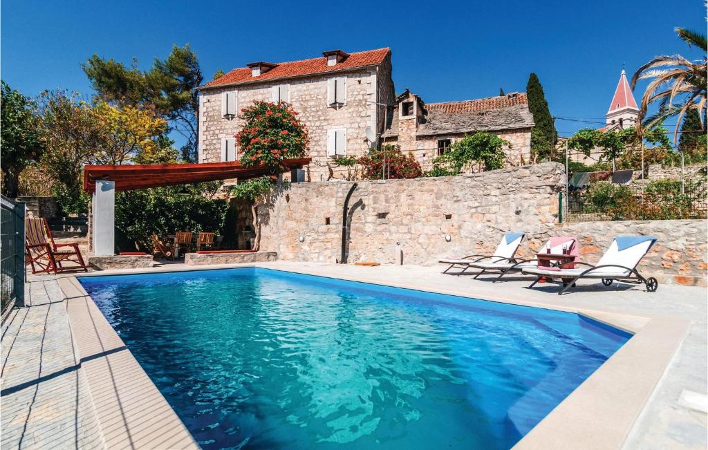 a swimming pool with two chairs and a house at Cozy Home In Bobovisca With Outdoor Swimming Pool in Ložišće