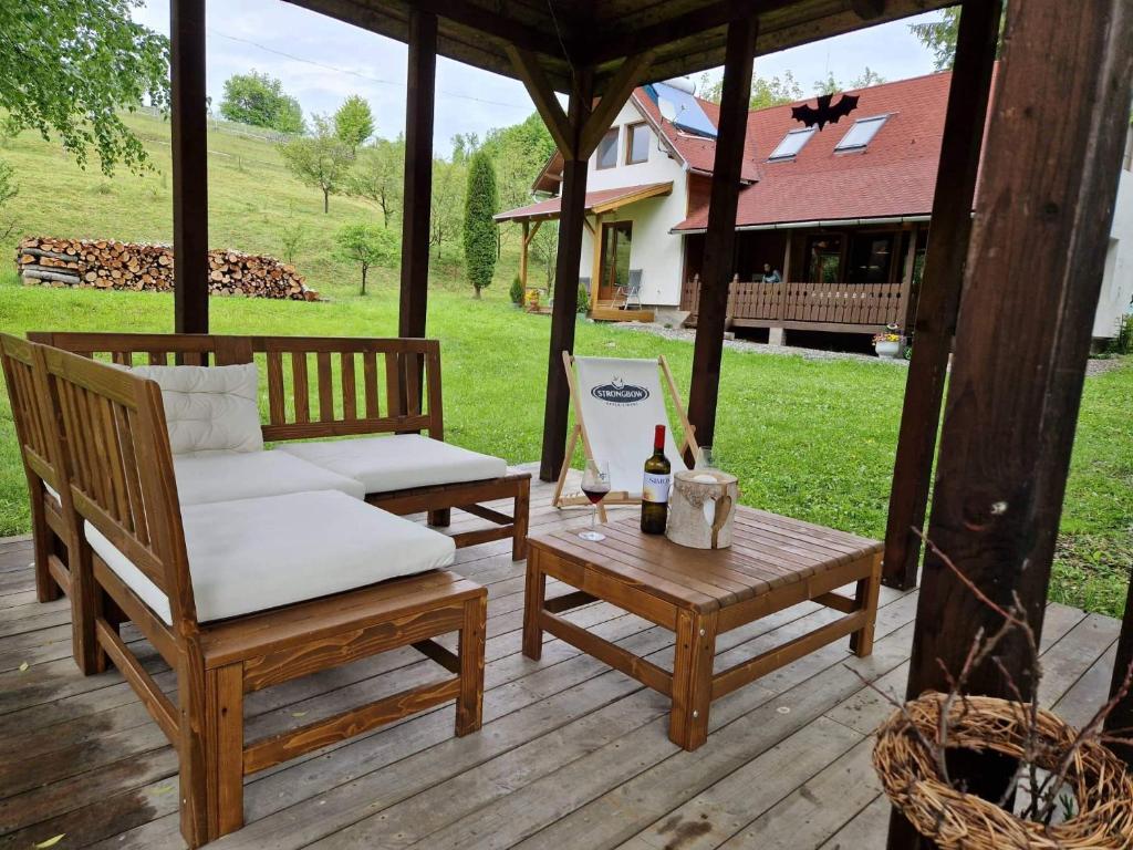 a porch with a chair and a table with a bottle of wine at Szőcs-birtok - The old house in Izvoare