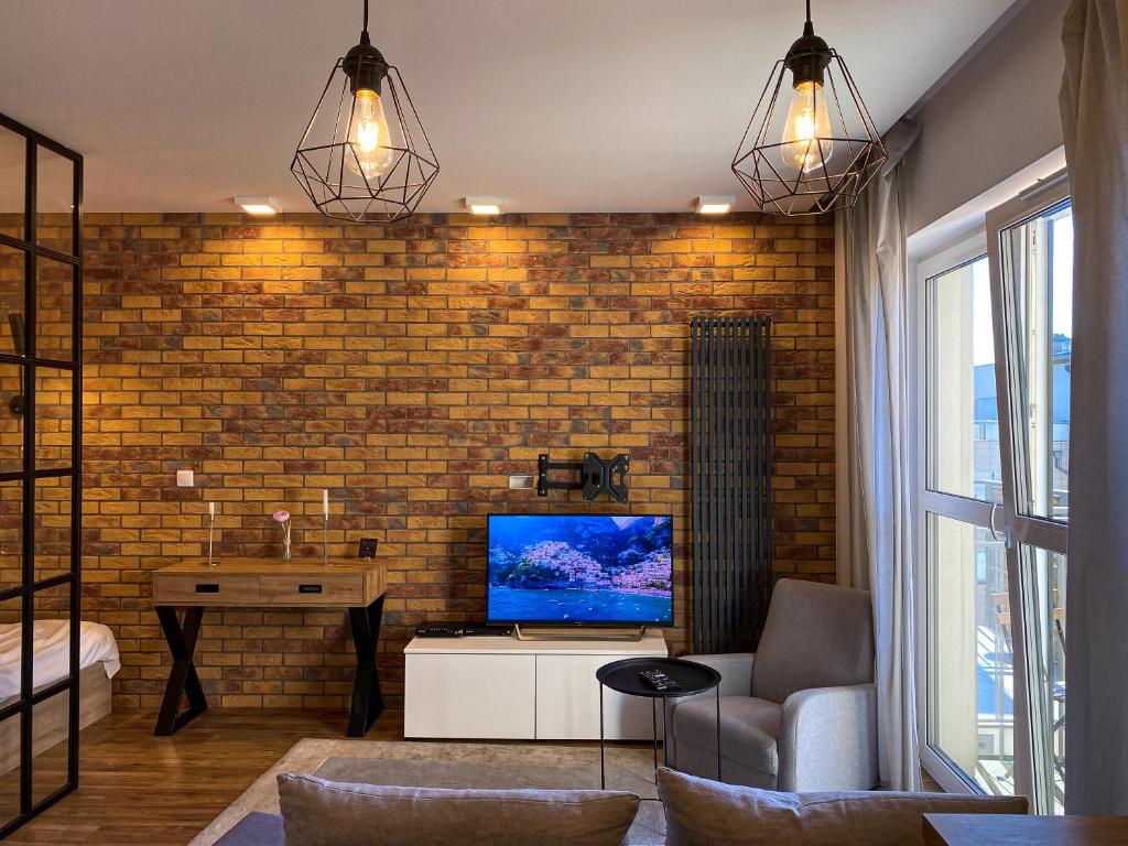 een woonkamer met een tv en een bakstenen muur bij BP Apartment in Toruń