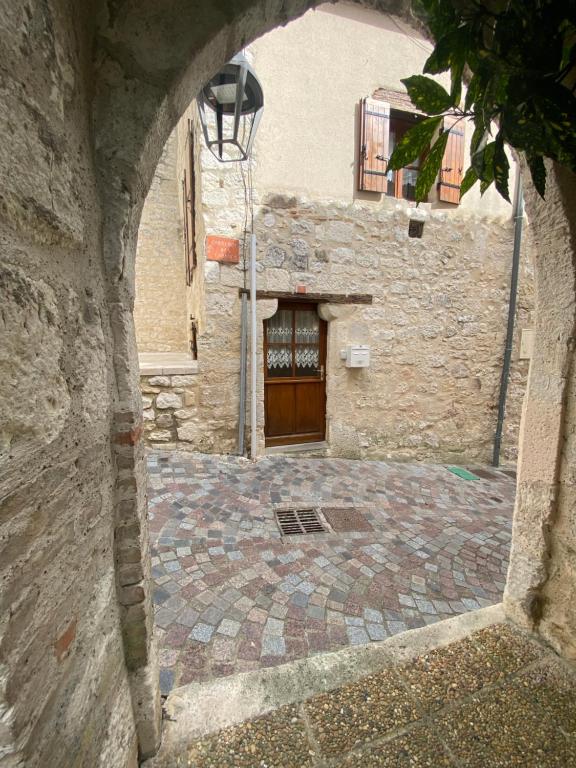 an archway leading to a building with a wooden door at Charmante maison de ville in Monflanquin