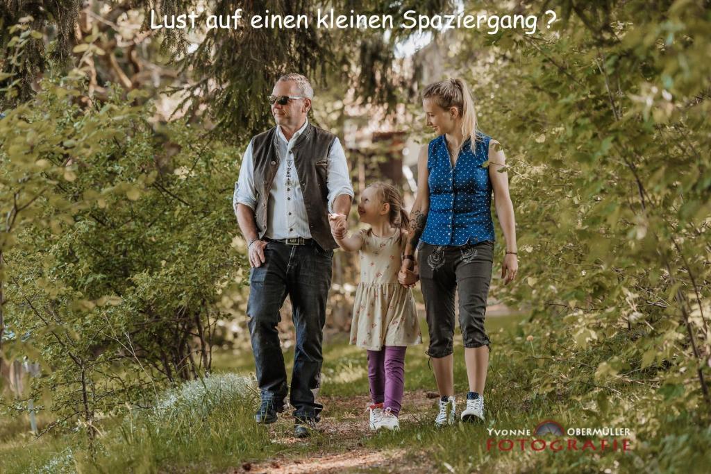 un hombre y una mujer caminando por un camino con una niña en Pension Fernblick, en Sankt Oswald