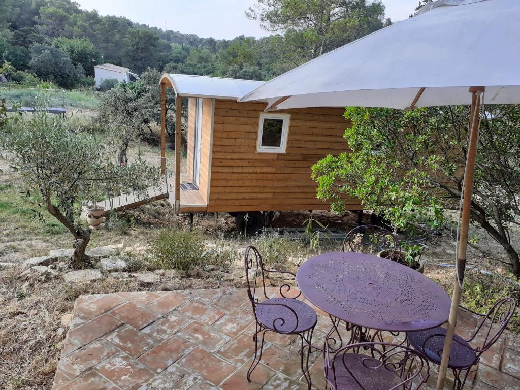 a picnic table with an umbrella and a cabin at Roulotte in Nîmes