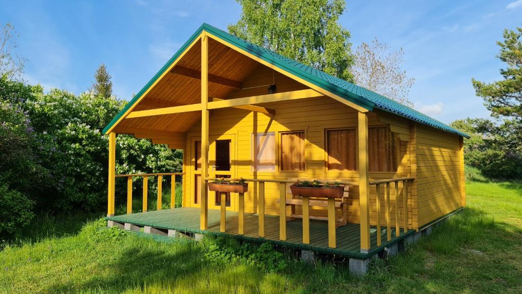 a yellow house with a green roof in a field at Jaunveiti in Bernāti