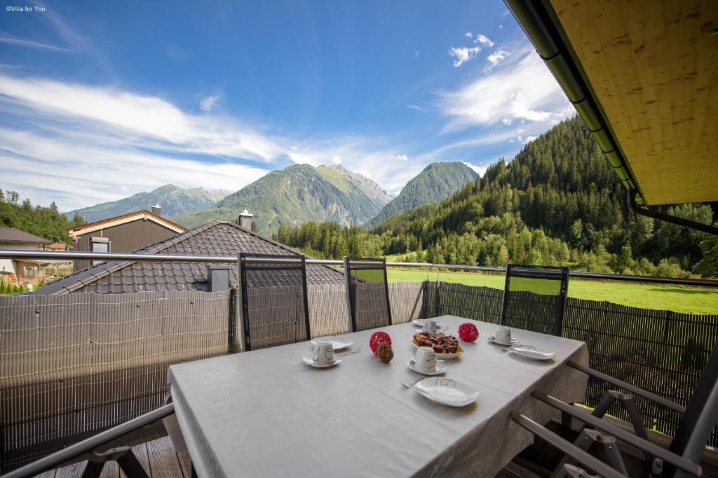 una mesa en un balcón con vistas a las montañas en Apartment Melina, en Neukirchen am Großvenediger