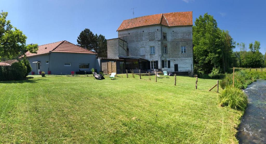 un viejo edificio con un patio de césped delante de él en Le moulin du Soudet, en Pernois