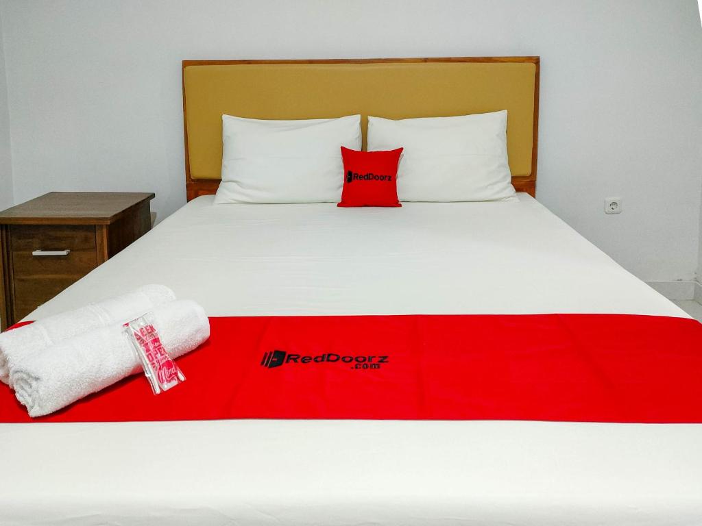 a bed with a red pillow and a red blanket at RedDoorz at Omah Candi Sari near Airport YIA in Yogyakarta